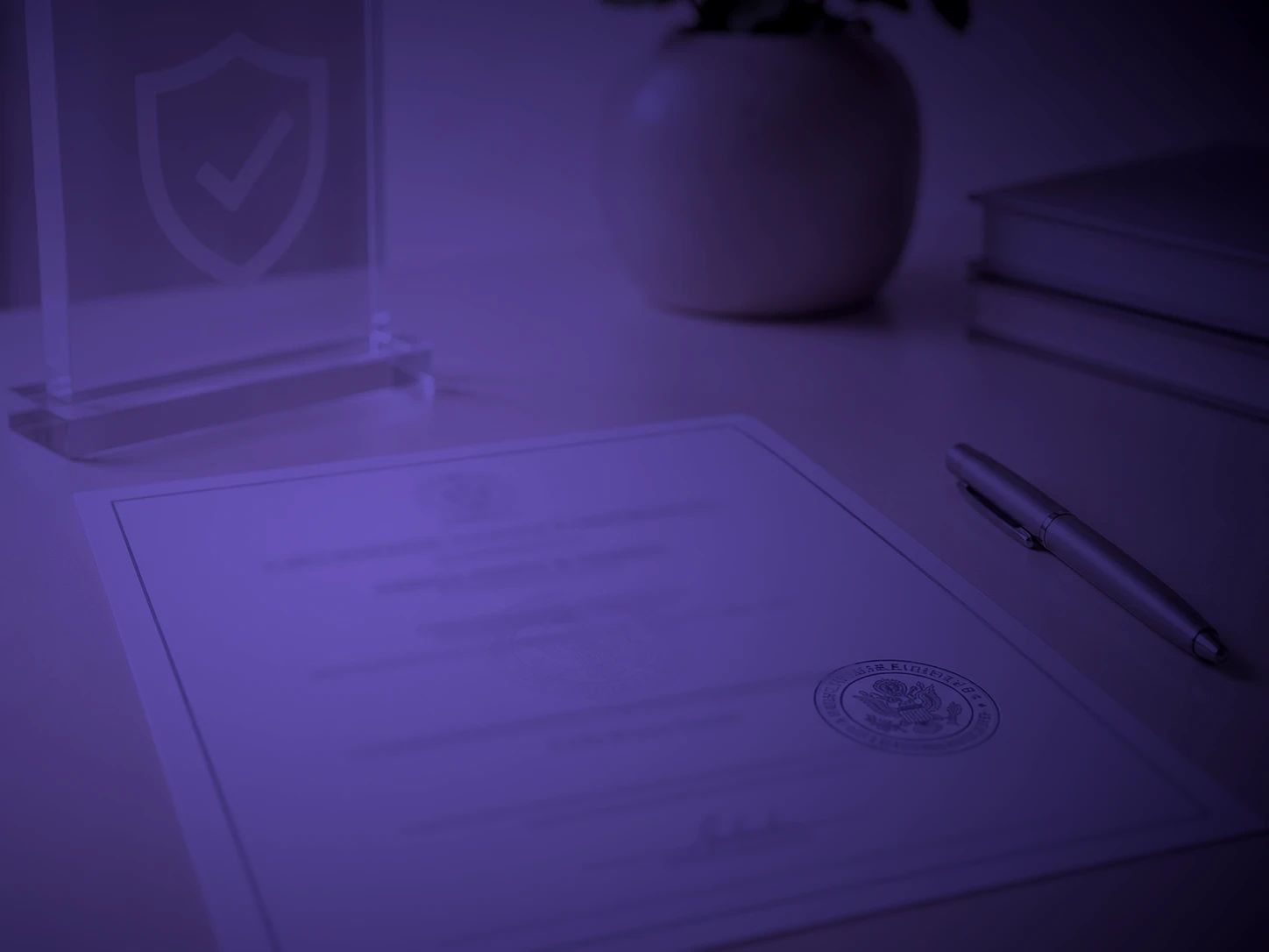 Cédula profesional con sello junto a una placa grabada con un escudo de verificación, iluminada por un foco violeta